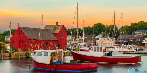 Rockport harbor in Massachusetts with fishing boats and waterfront buildings at dusk